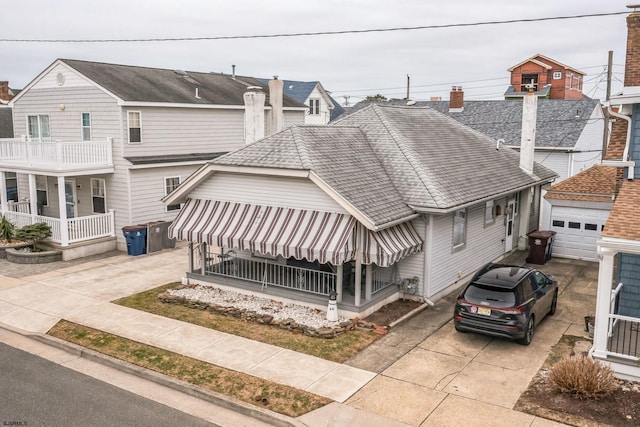 multi unit property with concrete driveway, roof with shingles, and an outdoor structure