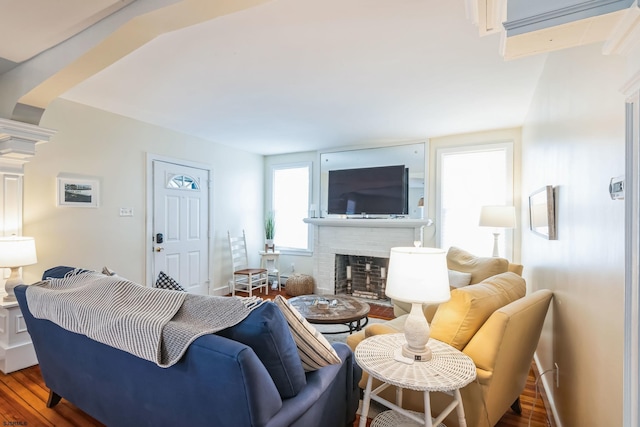 living room featuring a brick fireplace, baseboards, and wood finished floors