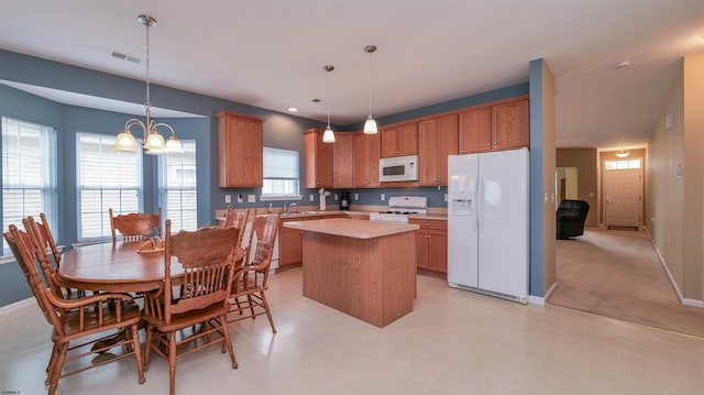 kitchen featuring white appliances, visible vents, a kitchen island, an inviting chandelier, and light countertops