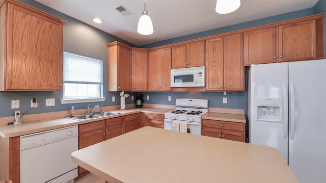 kitchen with white appliances, visible vents, a sink, hanging light fixtures, and light countertops