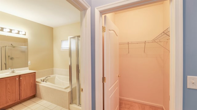 full bathroom featuring vanity, a stall shower, a spacious closet, a garden tub, and tile patterned floors