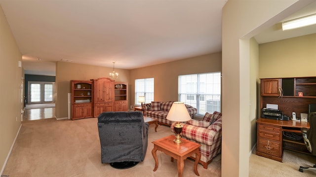 living room featuring a notable chandelier, baseboards, a wealth of natural light, and light carpet