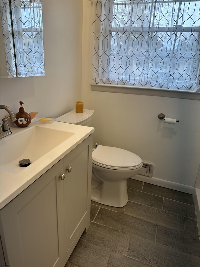 bathroom featuring toilet, vanity, and wood tiled floor