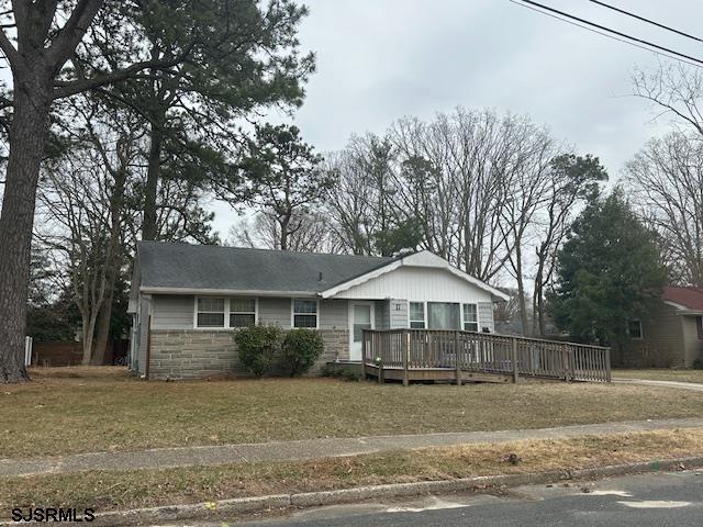 view of front of property featuring a deck, a front yard, and stone siding