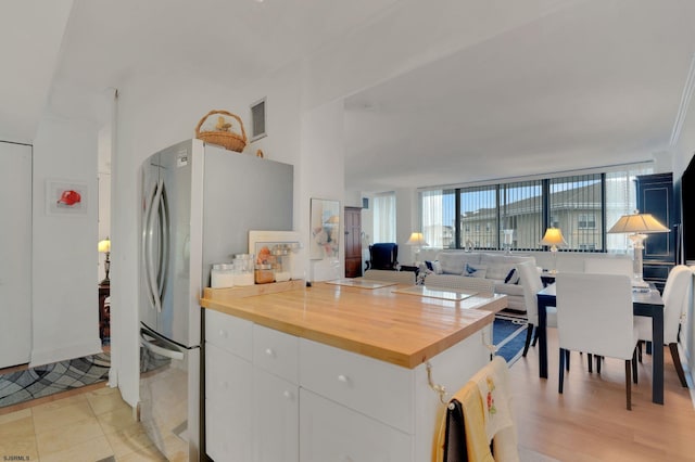 kitchen featuring visible vents, wooden counters, freestanding refrigerator, white cabinetry, and open floor plan