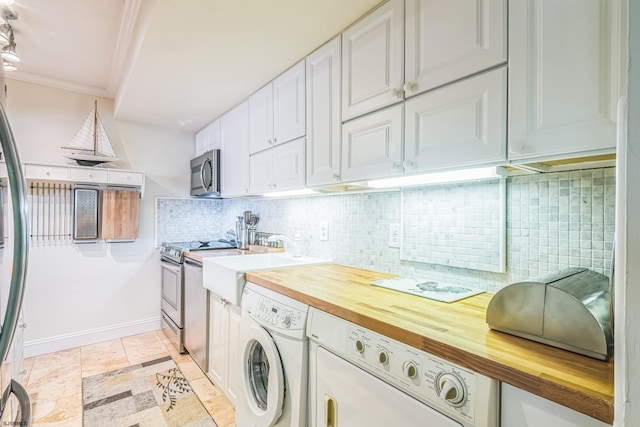 laundry area featuring ornamental molding, washer and dryer, light tile patterned floors, baseboards, and laundry area