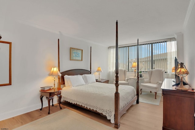 bedroom featuring light wood finished floors, baseboards, and ornamental molding