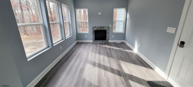 unfurnished living room with a fireplace, baseboards, and wood finished floors