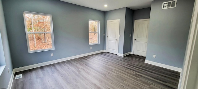 unfurnished bedroom with baseboards, visible vents, and dark wood-style flooring