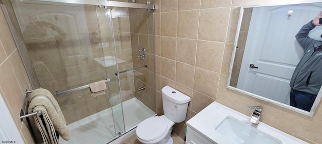 bathroom featuring vanity, toilet, tile walls, and a shower stall