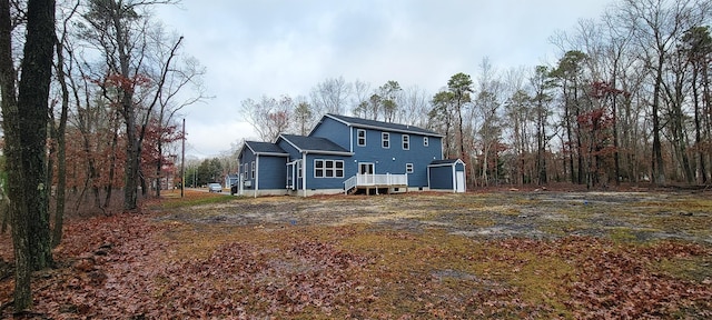 back of property with a deck, a storage shed, and an outbuilding