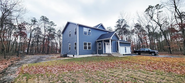 traditional home with a garage, central air condition unit, and driveway