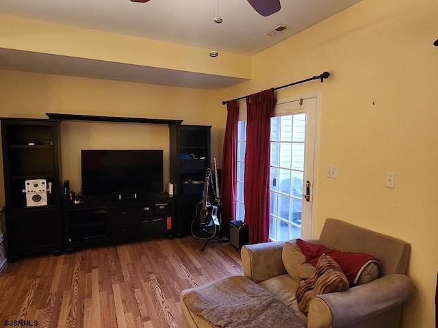 living area featuring ceiling fan, visible vents, and wood finished floors