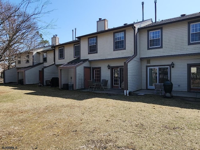 back of property with a patio area, a chimney, and a yard