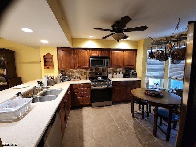 kitchen with ceiling fan, light countertops, decorative backsplash, appliances with stainless steel finishes, and a sink