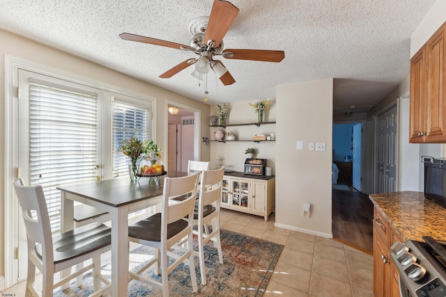 dining area featuring light tile patterned floors, baseboards, a textured ceiling, and a ceiling fan