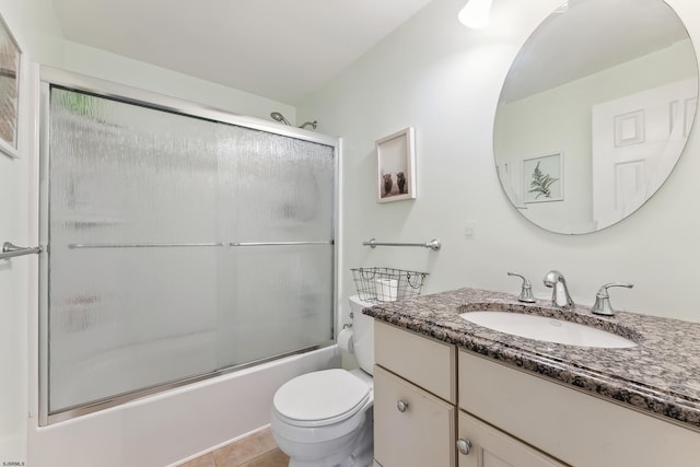 bathroom featuring tile patterned flooring, combined bath / shower with glass door, toilet, and vanity