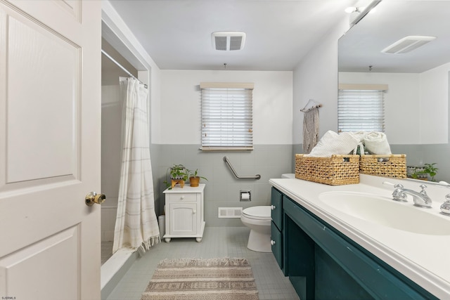 full bathroom with tile patterned flooring, visible vents, wainscoting, and tile walls