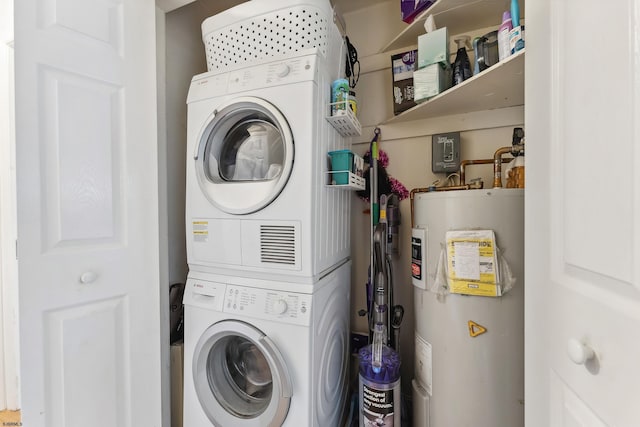 washroom with stacked washer / drying machine, water heater, and laundry area