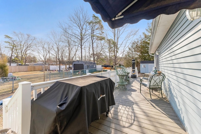 deck featuring a storage unit, an outbuilding, and fence