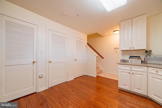 kitchen featuring light countertops, white cabinets, light wood-style floors, and baseboards