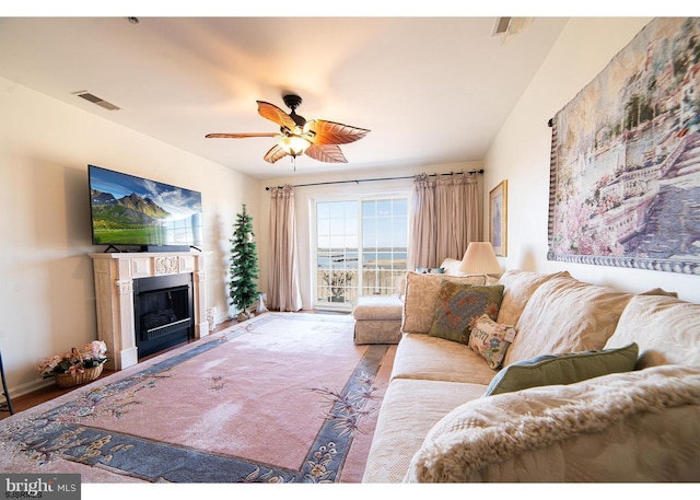 living area featuring visible vents, baseboards, a ceiling fan, and a fireplace