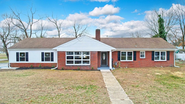 ranch-style home featuring brick siding, a chimney, and a front yard