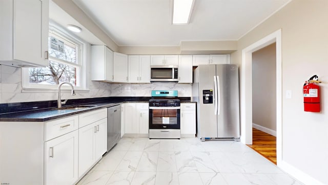 kitchen with marble finish floor, a sink, dark countertops, tasteful backsplash, and appliances with stainless steel finishes