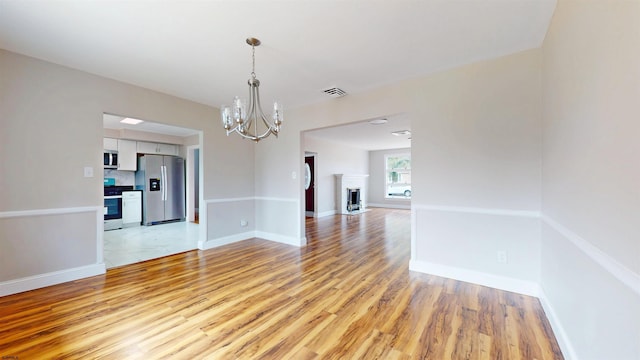 unfurnished room featuring a chandelier, visible vents, baseboards, and light wood-style floors