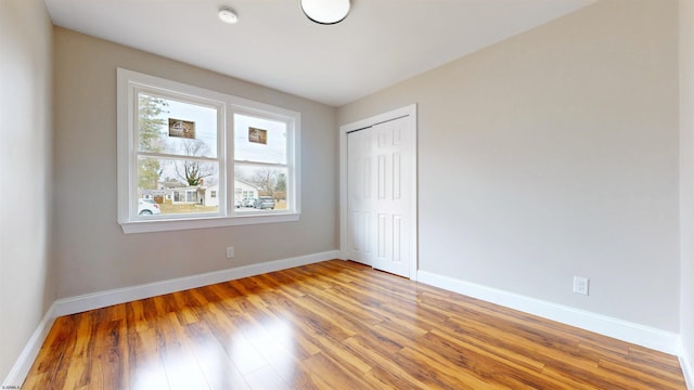 unfurnished bedroom with a closet, light wood-type flooring, and baseboards