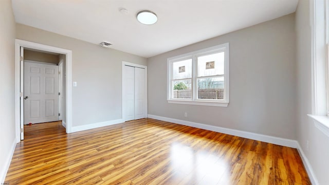 unfurnished bedroom featuring light wood finished floors, visible vents, a closet, and baseboards