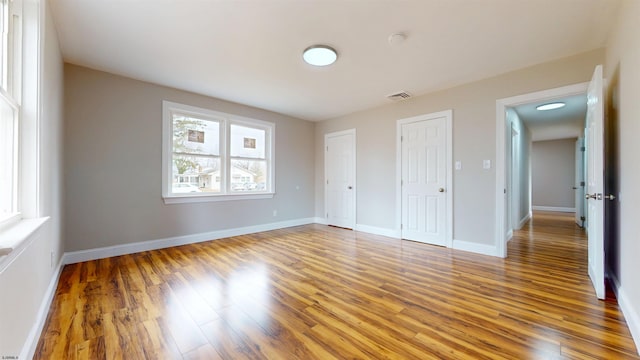 unfurnished bedroom featuring visible vents, baseboards, and wood finished floors