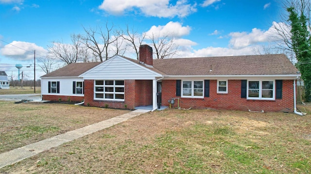 ranch-style house featuring brick siding, a chimney, a front lawn, and a shingled roof