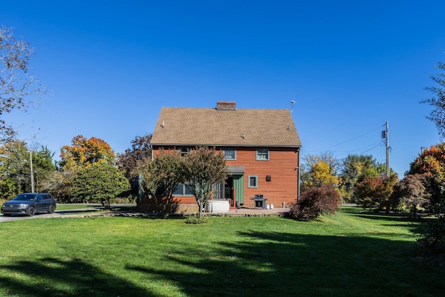 rear view of house featuring a lawn and a chimney