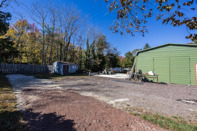 view of yard featuring an outdoor structure, a shed, and fence