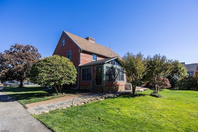 view of property exterior featuring entry steps, a yard, roof with shingles, and a chimney