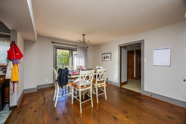 dining area featuring baseboards, an inviting chandelier, and hardwood / wood-style flooring