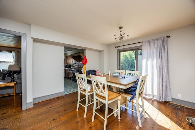 dining space with baseboards, visible vents, wood-type flooring, and an inviting chandelier