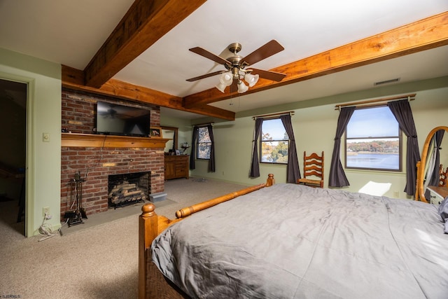 carpeted bedroom with visible vents, beam ceiling, and a brick fireplace