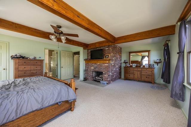 bedroom featuring beamed ceiling, a brick fireplace, a ceiling fan, and carpet