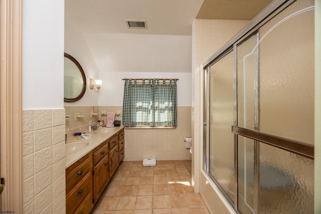 bathroom with visible vents, double vanity, tile patterned floors, tile walls, and a sink