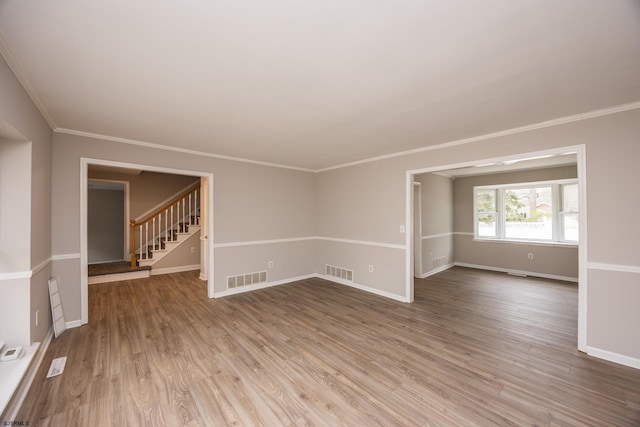 unfurnished room with visible vents, stairway, and wood finished floors