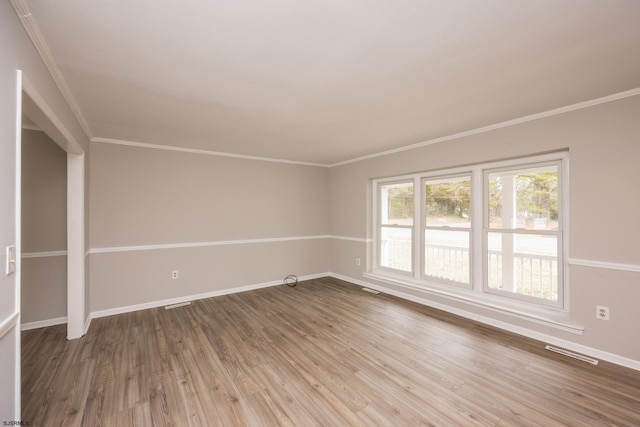 spare room with baseboards, wood finished floors, and crown molding