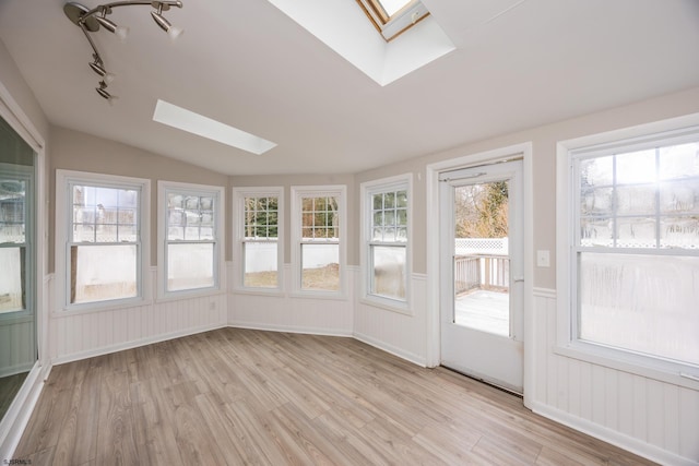 unfurnished sunroom with vaulted ceiling with skylight and rail lighting