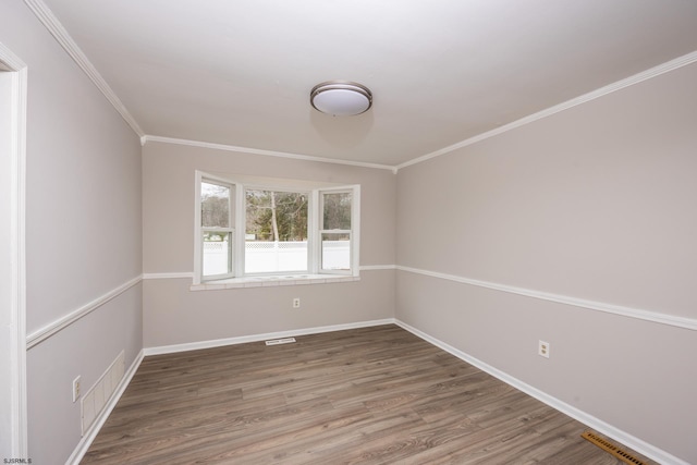 spare room featuring visible vents, crown molding, baseboards, and wood finished floors