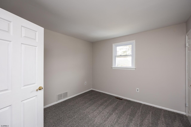 empty room with visible vents, baseboards, and dark colored carpet