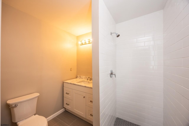 bathroom featuring tile patterned flooring, toilet, vanity, and a tile shower