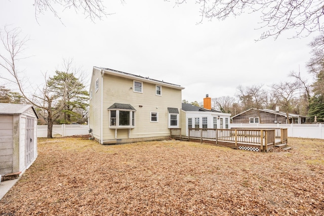 back of property with an outbuilding, a deck, and a fenced backyard