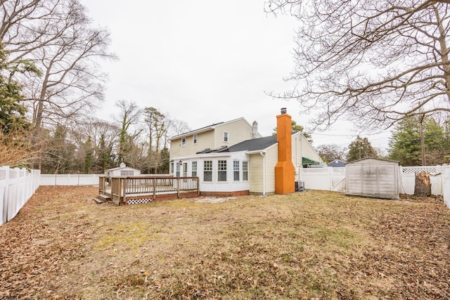 back of house with a wooden deck, a chimney, a storage shed, an outdoor structure, and a fenced backyard