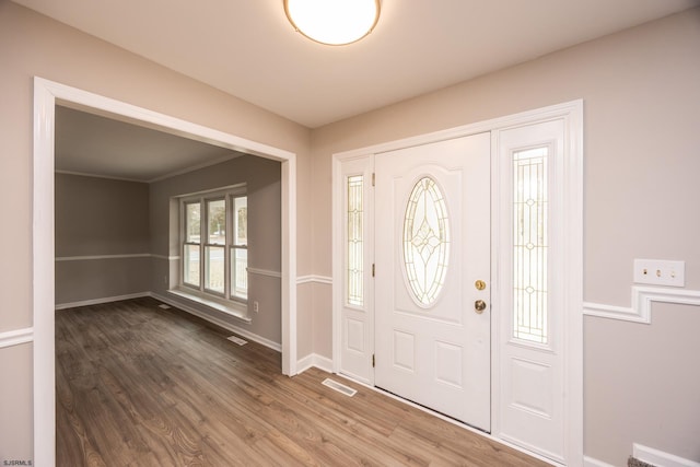 foyer entrance featuring wood finished floors, visible vents, and baseboards